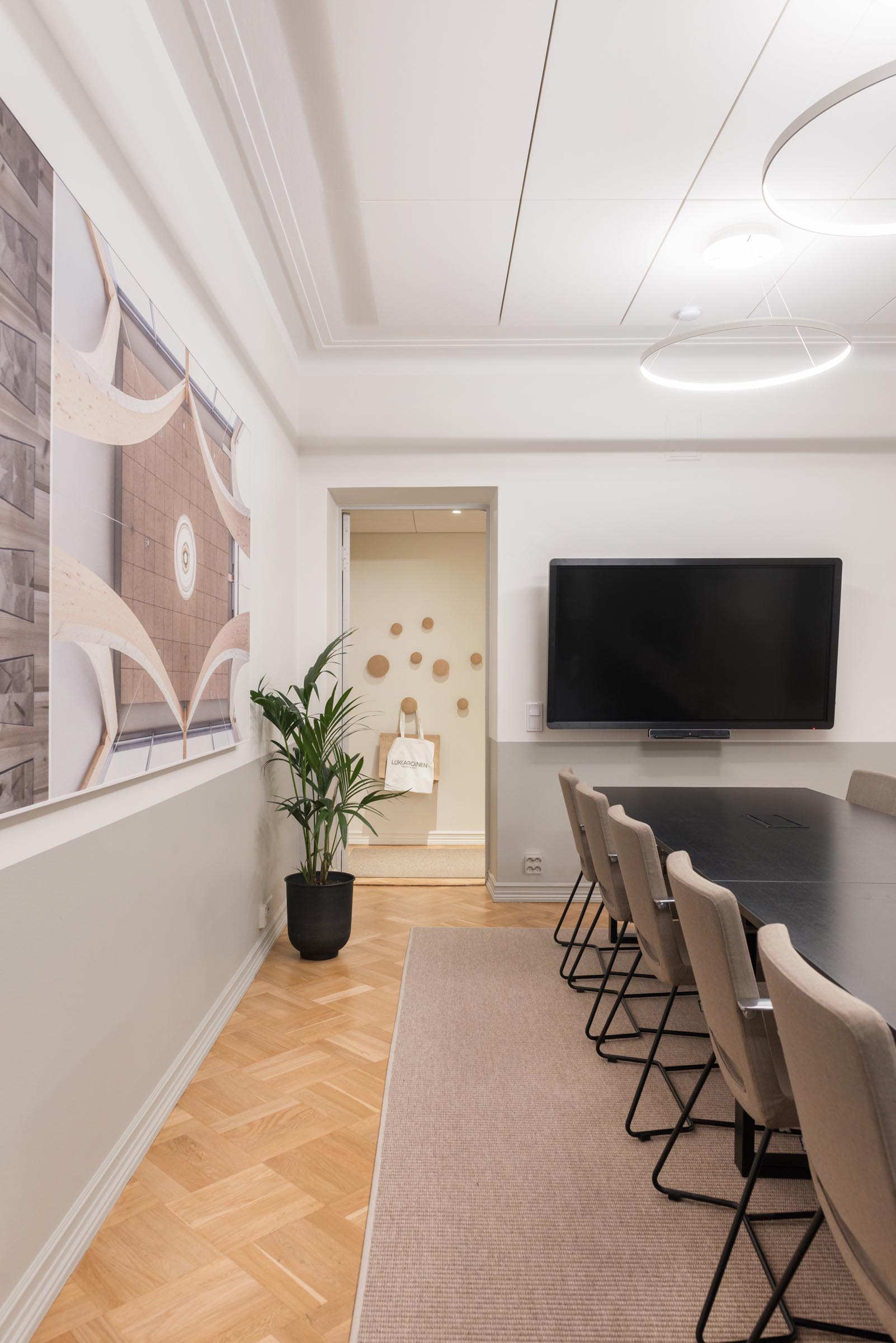 Lukkaroisen Helsingin toimiston uusi neuvottelumaailma, neuvotteluhuone, jossa pitkä pöytä tuoleineen ja tv.